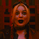 Margot Robbie's Harley Quinn is bathed in red light and looking surprised in The Suicide Squad.